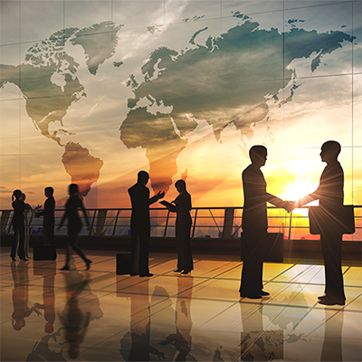 Business people at sunset with a world map superimposed behind them.