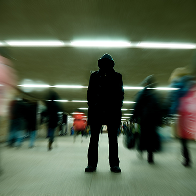 Image of a man in shadow surrounded by people in motion.